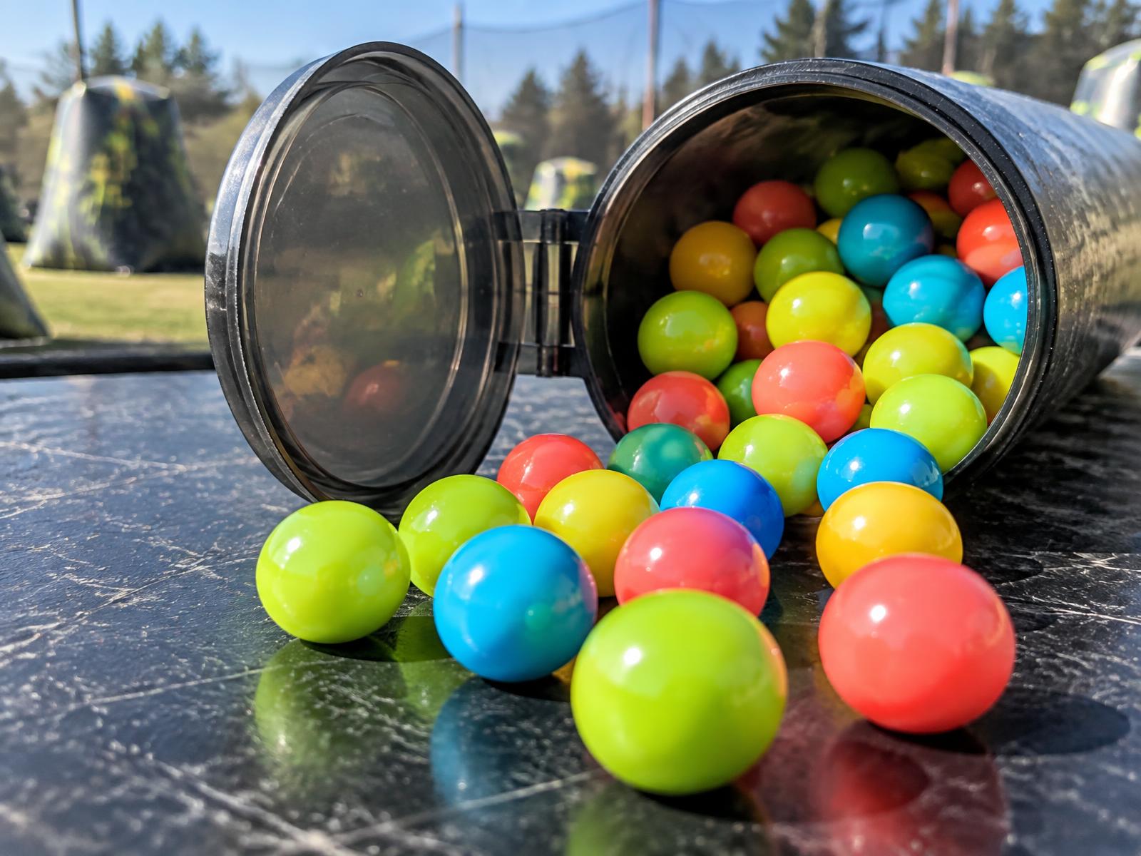 Bright yellow, lime, blue, and coral paintballs spilling from a pod