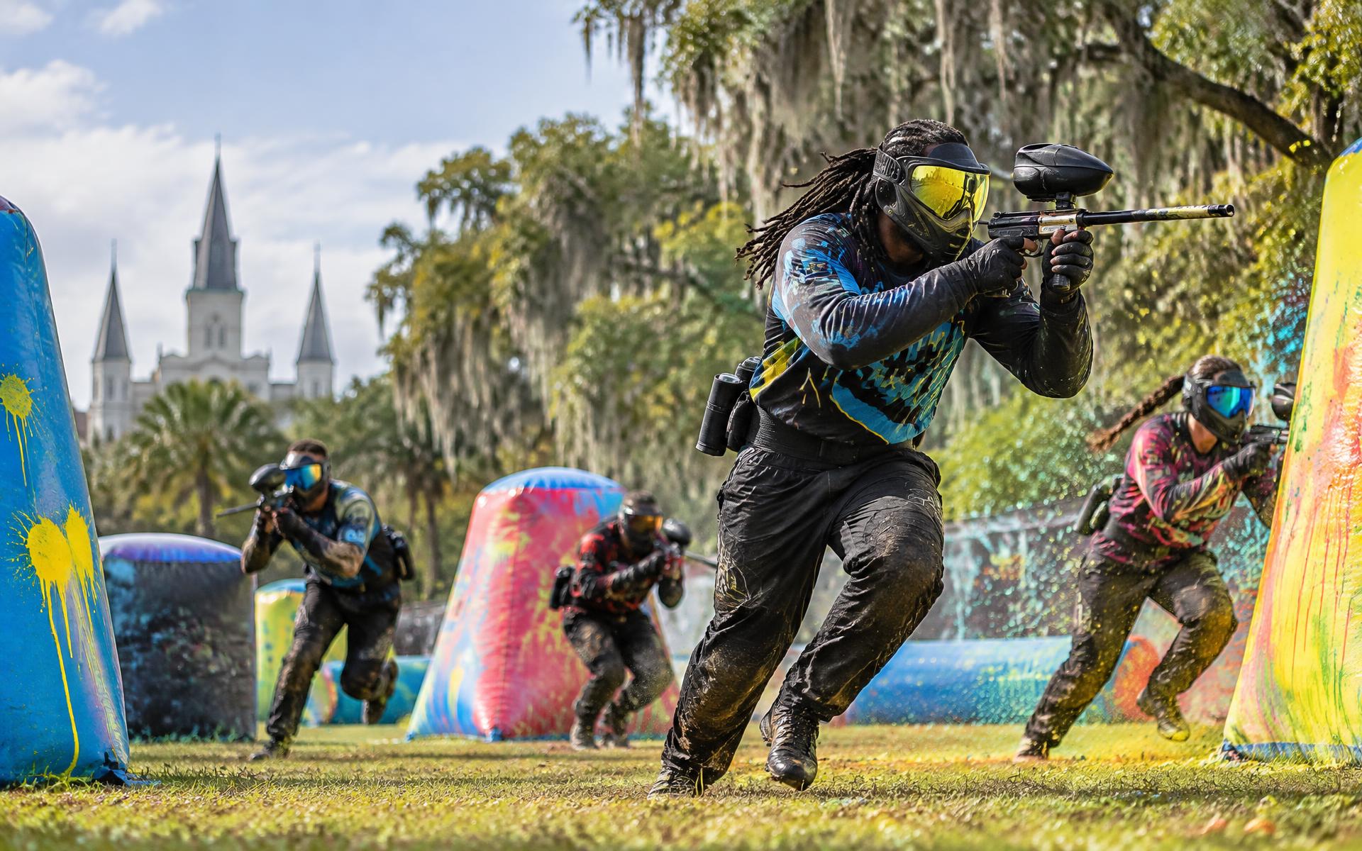 Paintball players racing across a colorful outdoor field in New Orleans